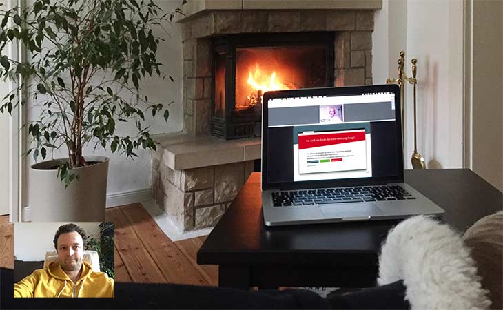 Laptop mit laufendem Webinar vor Kamin
